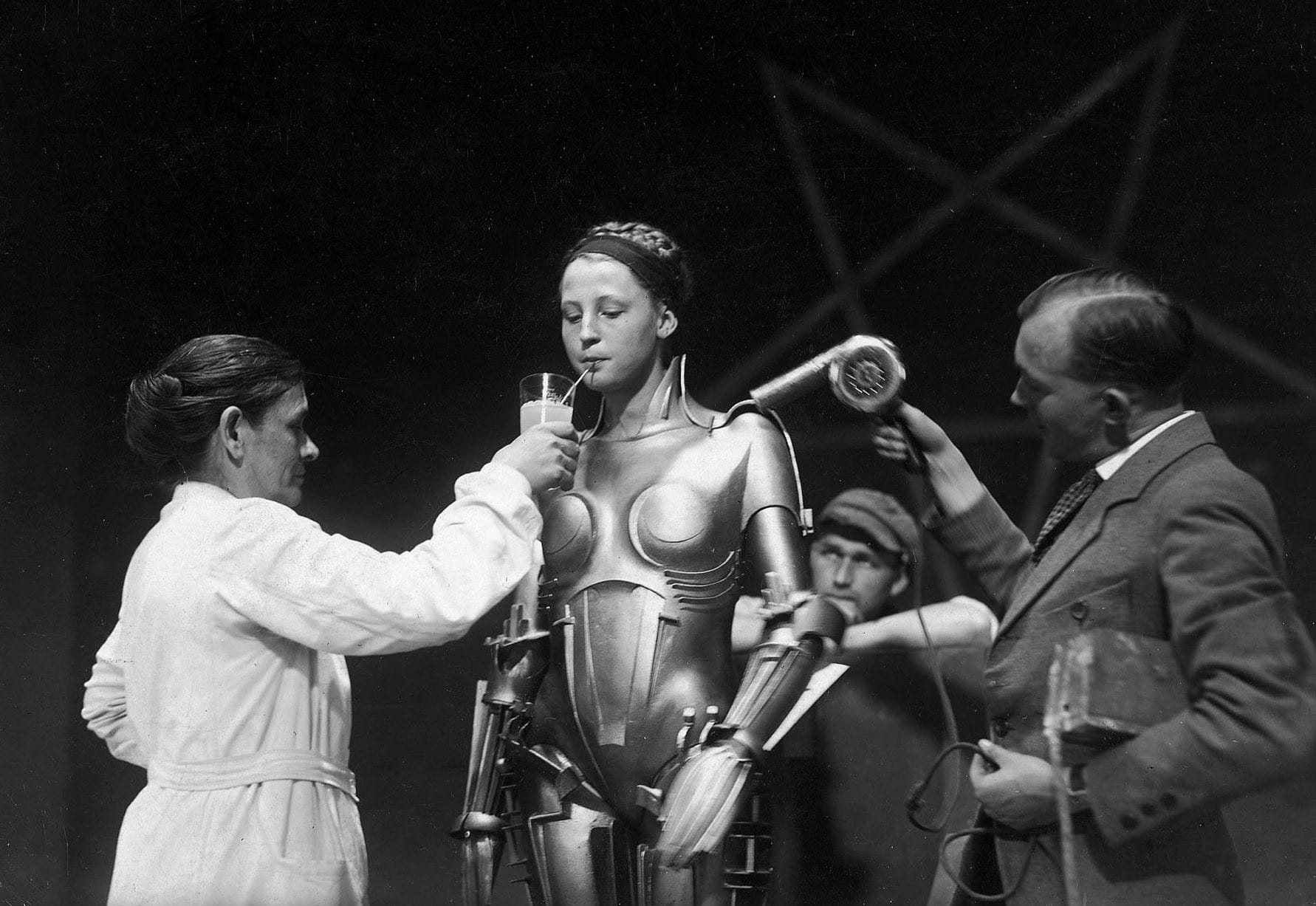 Brigitte Helm cools off on the set of Metropolis by drinking something with a straw, 1927.